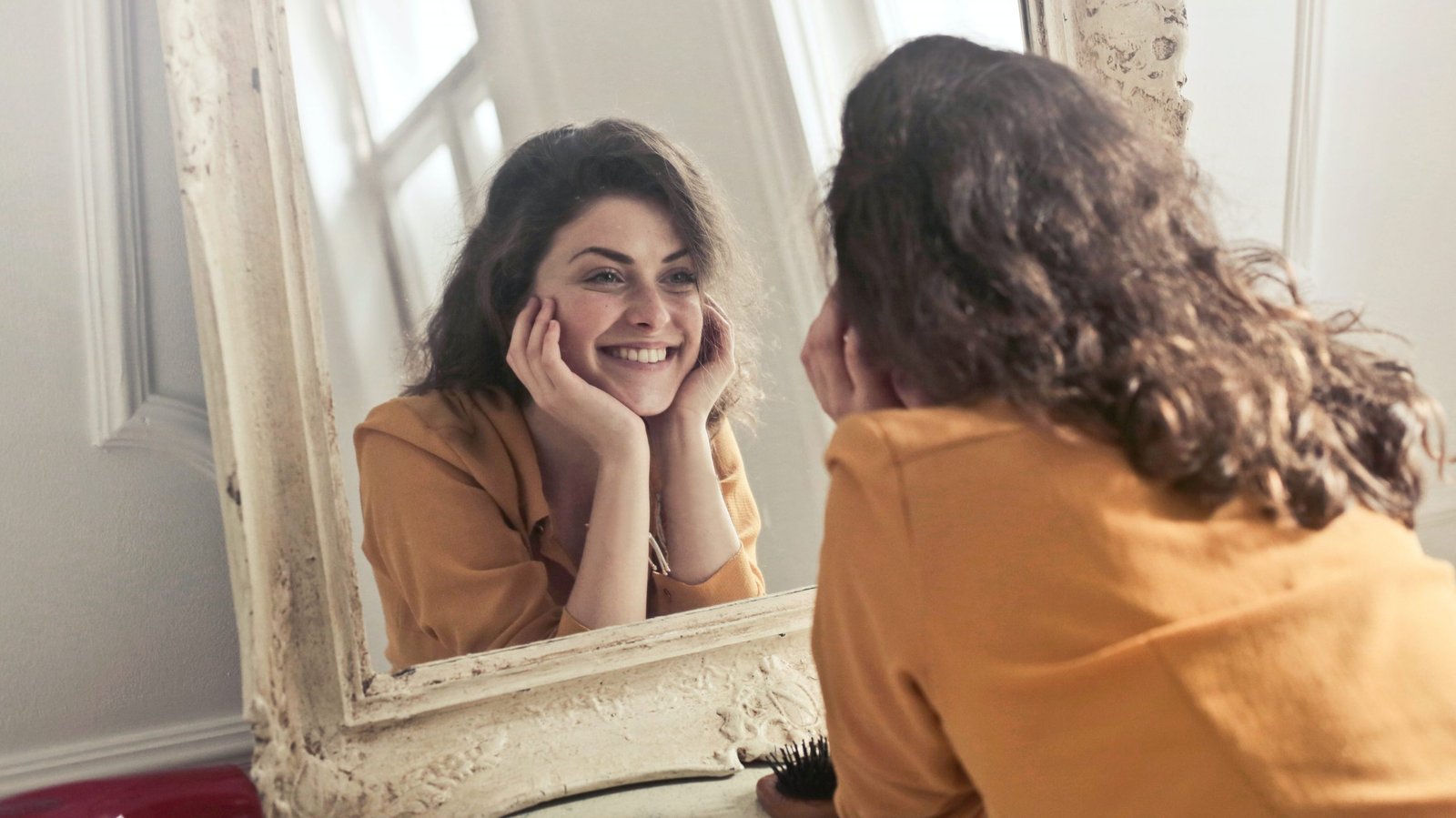 Woman Smiling at herself in a mirror as self care